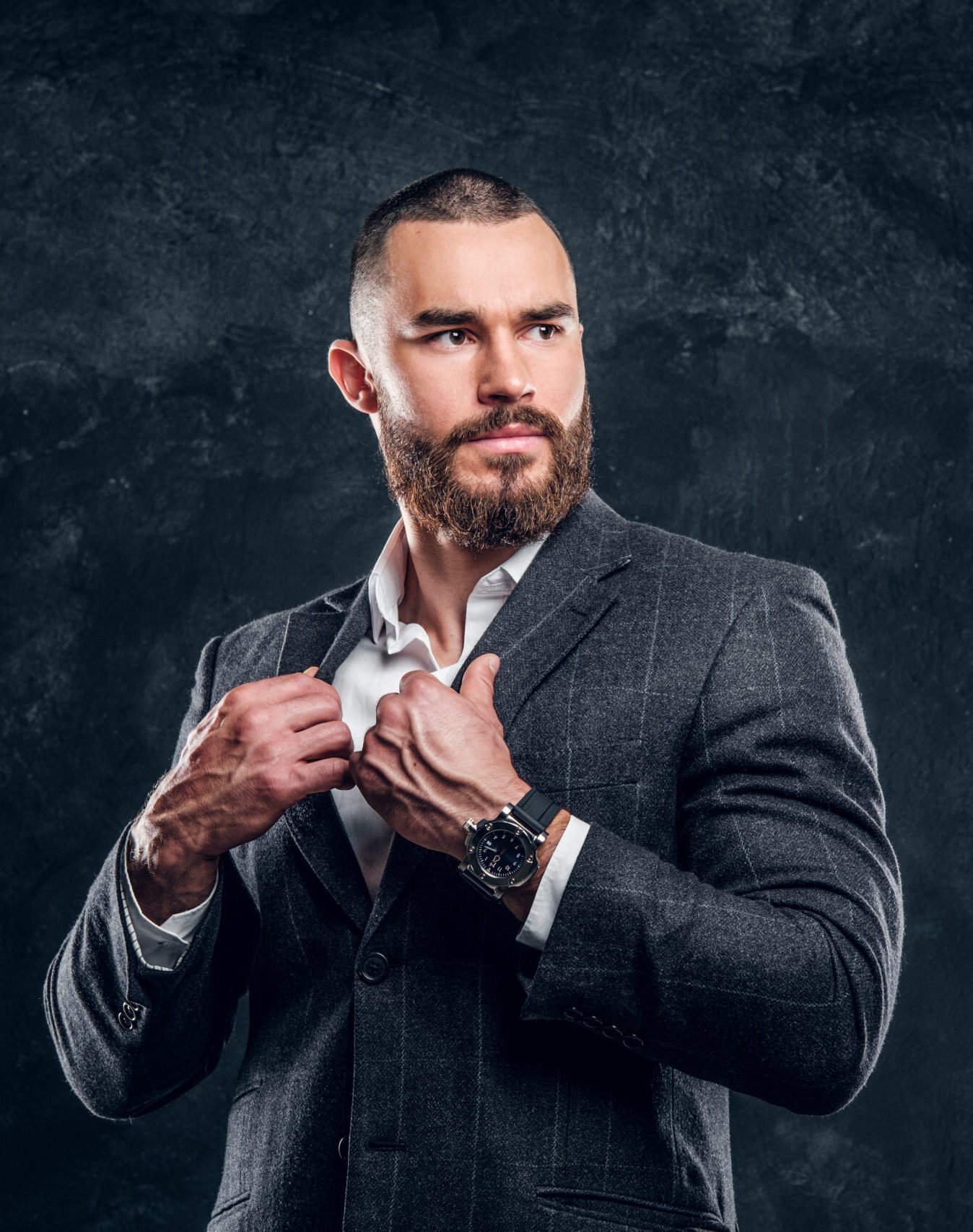 Handsome sucessful buisnessman is posing for photographer on the dark background.